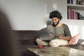Man sitting on couch in living room with laptop and credit card
