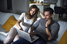 Man and woman sitting on a sofa working on a laptop