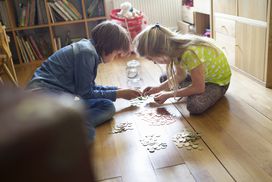 Two children counting coins together on the floor