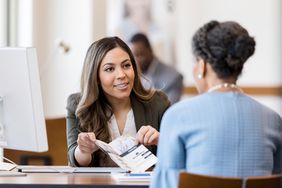 Bank employee explains services to new customer using brochure