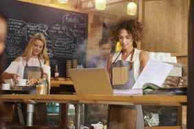 Coffee shop owner with laptop going over bills
