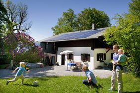 family playing outside in front of their home that has a solar panel system